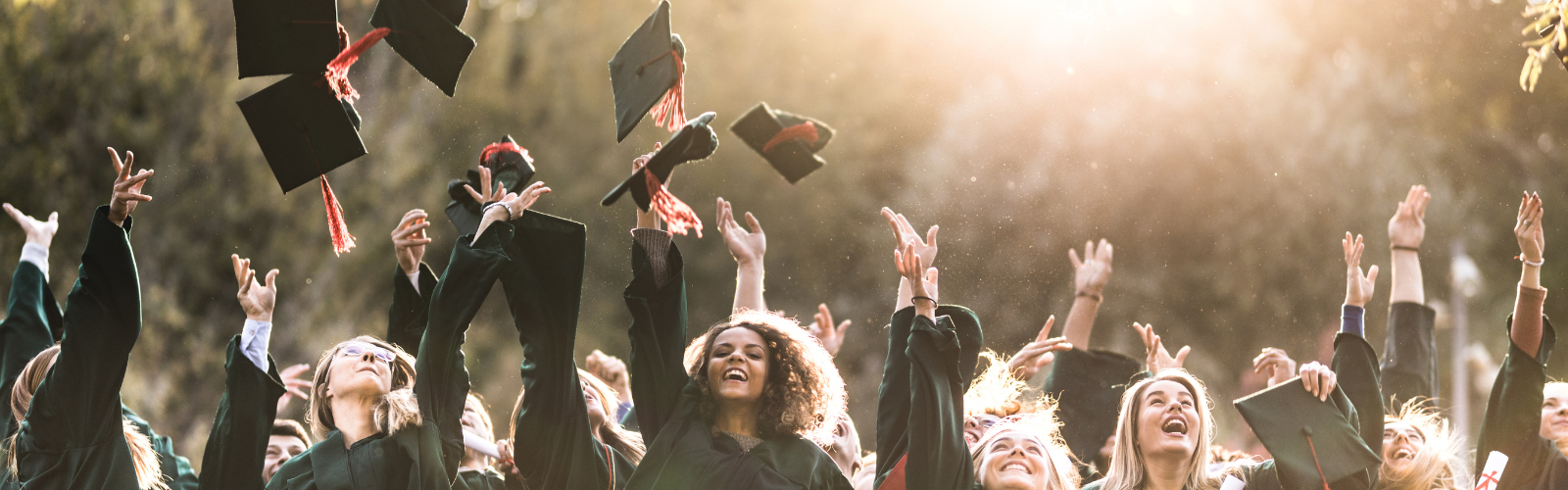 graduates standing on a hill tossing their caps in the air