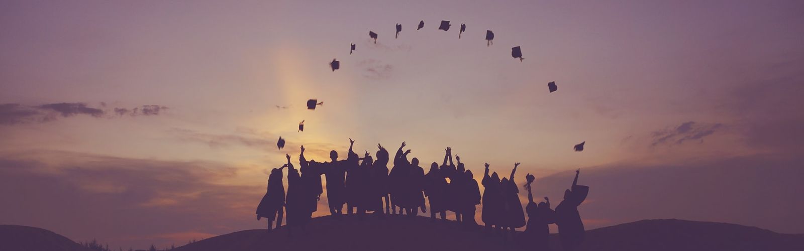 graduates standing on a hill tossing their caps in the air