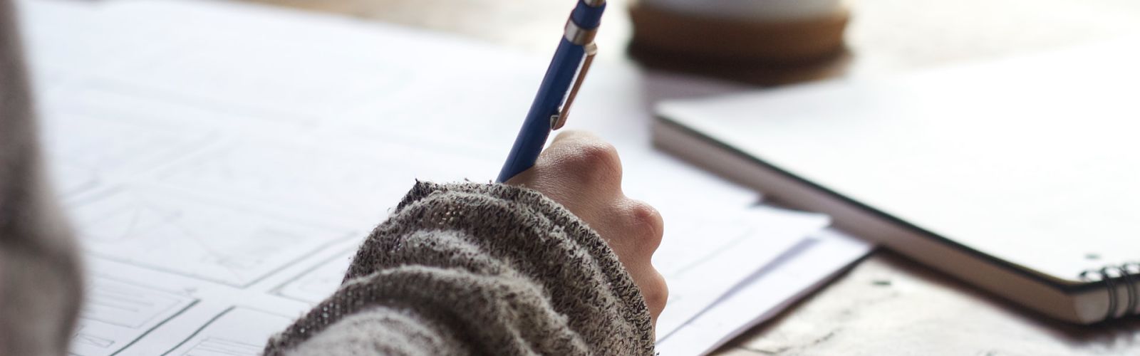 close up of hand writing on desk