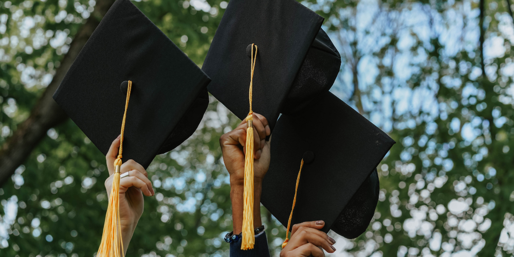 Graduates holding up graduation caps