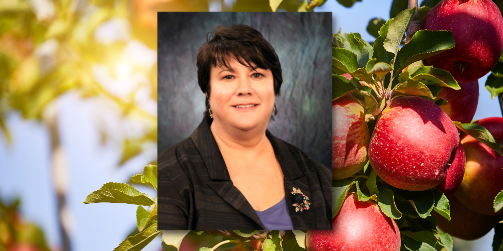 Photo of Vicki Houston with an apple orchard in the background