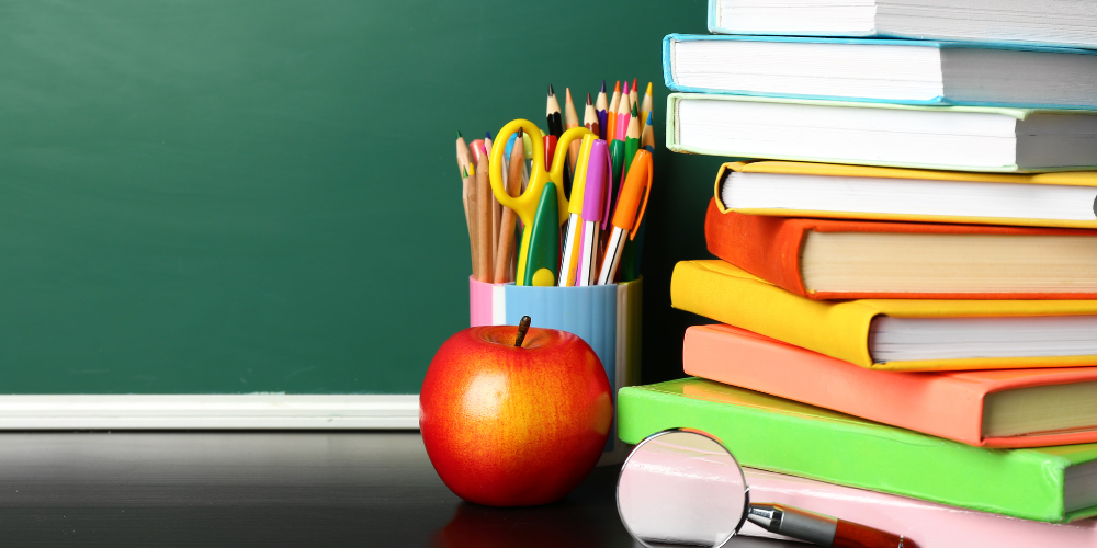 Apple, book and school supplies on a desk