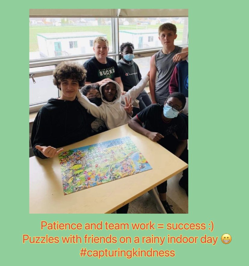Students work together to complete a puzzle and look proud